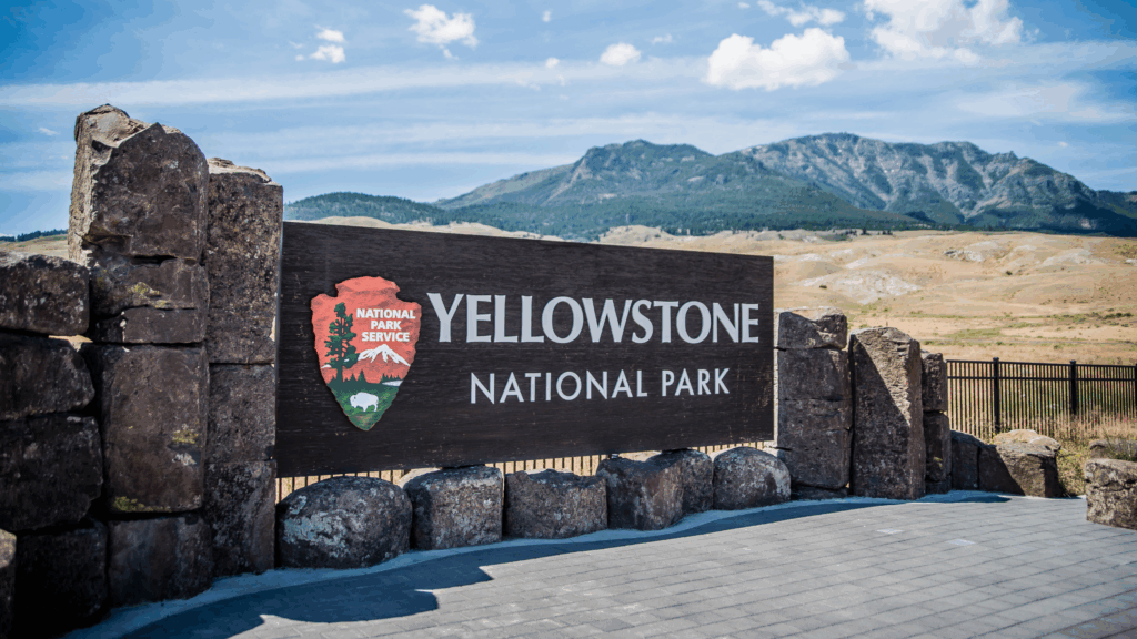 Yellowstone National Park sign at entryway with mountains in the background