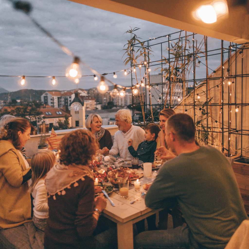 Group of people sharing a dinner on the patio under bistro lights