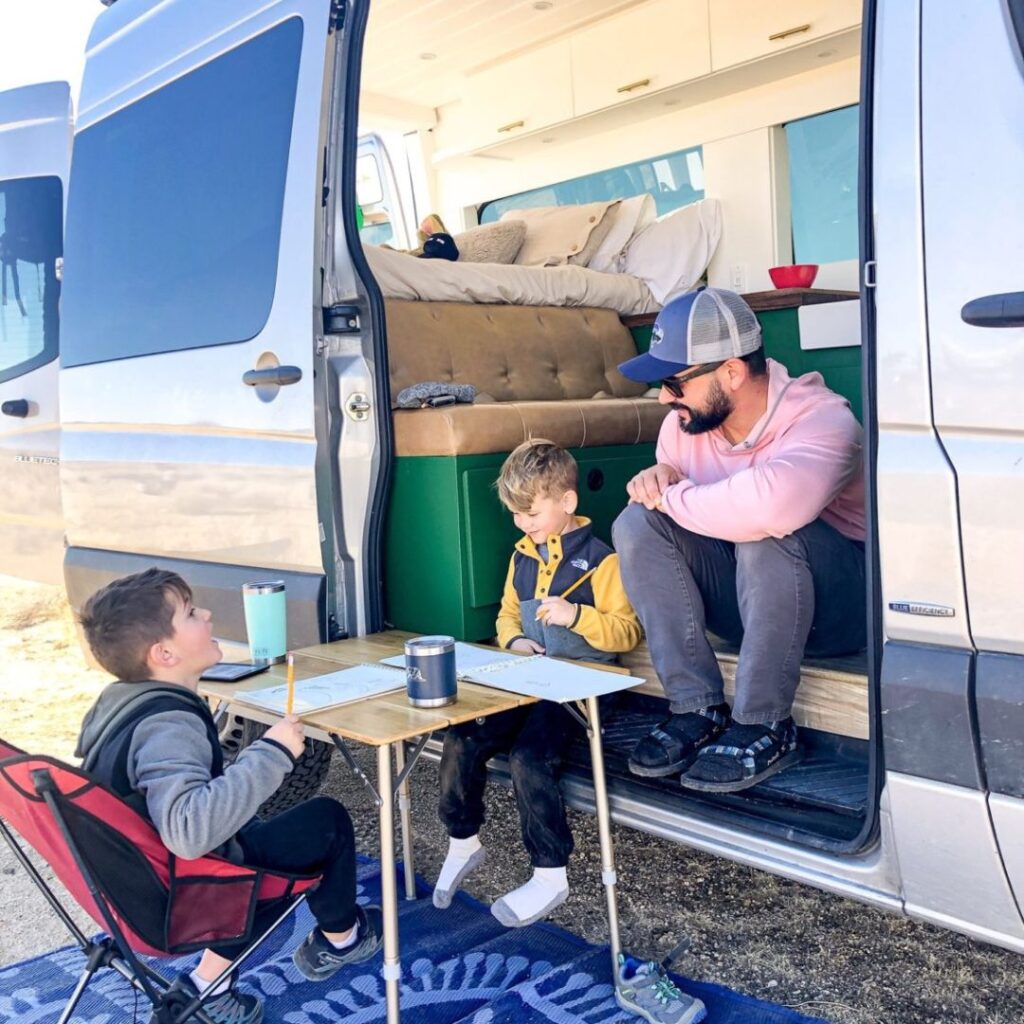 Family camping outside RV having a class session at a desk