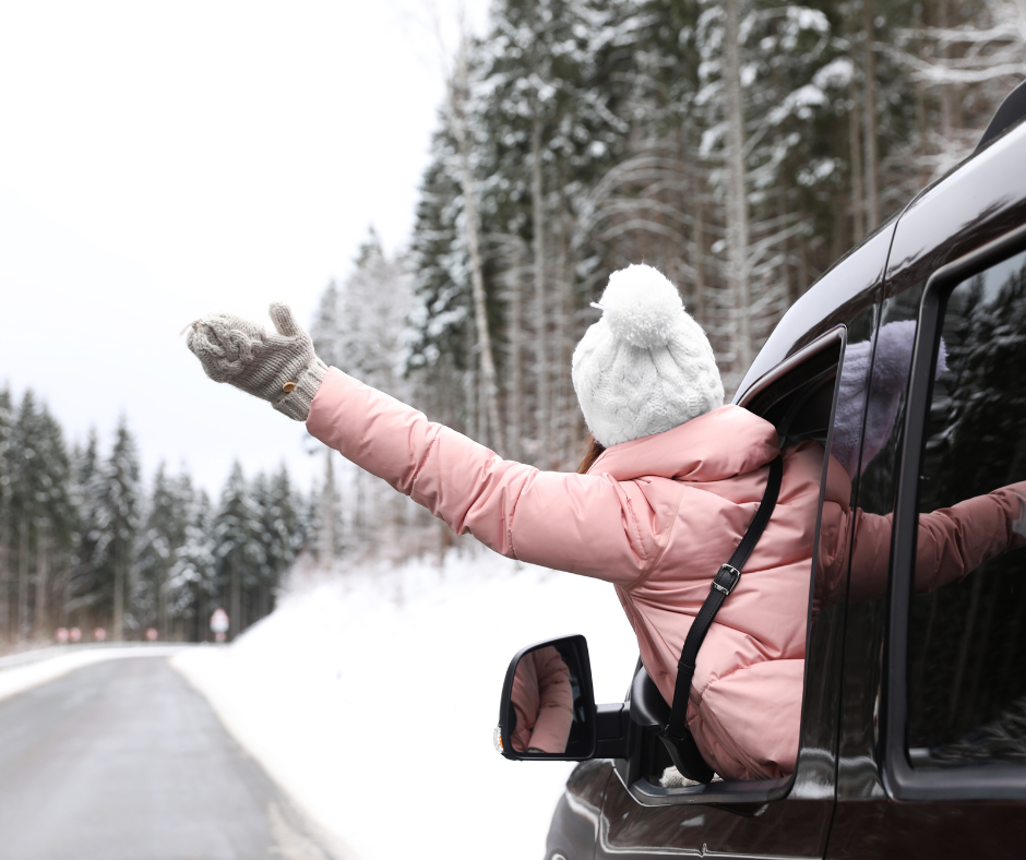 Winter RV or car traveling with a girl sticking hand out the window